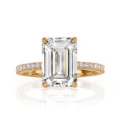 an emerald - cut diamond engagement ring with pave diamonds on the band and shoulders