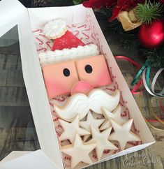 a decorated cookie in a box with santa clause on it's face and stars