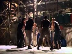 a group of men standing around each other in front of a metal structure at night