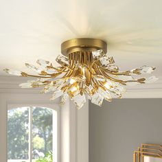 a gold chandelier hanging from the ceiling in a room with white walls and windows