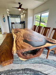 a large wooden table sitting in the middle of a living room next to a window