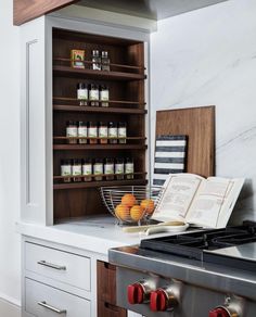 an open book is sitting on the counter next to some oranges and other items