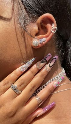 a close up of a person with many different rings on their fingers and ear nails