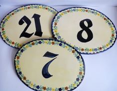 three decorated plates with numbers on them sitting in a white tablecloth covered box, one has the number seven