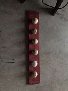 a wooden rack with baseballs in it on the floor next to a chair and table