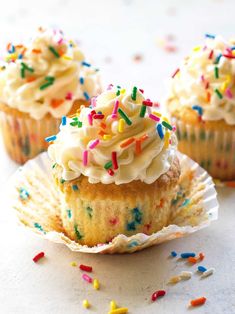 three cupcakes with white frosting and sprinkles