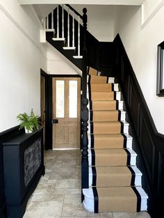 the stairs are painted black and white with striped carpet on each side, along with a potted plant