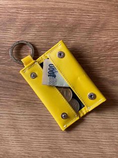 a yellow leather wallet with money in it and a metal keychain hanging from the front