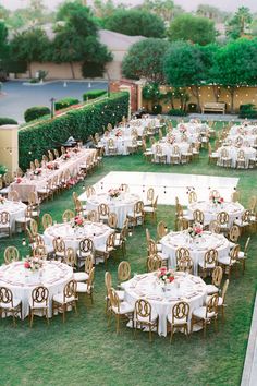 an outdoor wedding reception with tables and chairs set up in the middle of a lawn