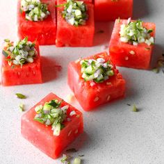 watermelon cubes with chopped green onions and seasoning on them sitting on a white surface