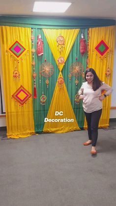 a woman standing in front of a green and yellow backdrop with decorations on it's sides