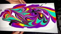 a person holding up an apple laptop with colorful swirls on the back and sides