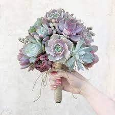 a bouquet of succulents is being held by a woman's hand