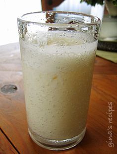 a glass filled with liquid sitting on top of a wooden table