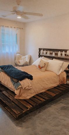 a bed made out of wooden pallets in a room with white walls and windows