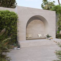 an outdoor seating area with stone walls and plants around it, surrounded by greenery