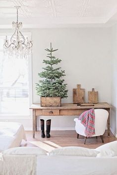 a small christmas tree sitting on top of a wooden table next to a white couch