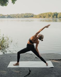 a woman is doing yoga by the water