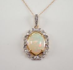 "Yellow Gold Diamond and Opal Pendant Necklace. The Necklace is set with one Oval Opal Cabochon in the center.  This Opal measures 11 X 9 mm and weighs 2 carats.  There are twenty-eight Round Brilliant Diamonds set in this pendant. These diamonds are H color, SI/I1 clarity and weigh a total of .20 carat.  The pendant is 10K Yellow Gold and comes with an 18\" 10K Yellow Gold chain and together weigh 2.4 grams.  The pendant measures 25 X 14 mm with the bail.  This necklace will be accompanied by a White Necklace With Stone Setting For Formal Occasions, Formal White Necklace With Stone Setting, Oval Multi-stone Necklace For Wedding, Oval Stone Setting Necklaces For Anniversary, Oval Stone Set Necklaces For Anniversary, Oval Stone Setting Necklace For Anniversary, Antique Diamond Necklace, October Gemstone, Wide Wedding Rings