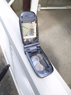 an open cell phone sitting on top of a white fence