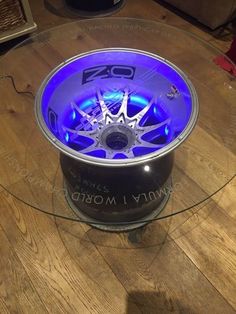 a glass table with a wheel on top of it and blue lights in the center