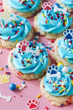 cookies with blue frosting and sprinkles on a pink surface