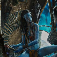 a woman dressed in blue sitting on the ground next to a man with dreadlocks