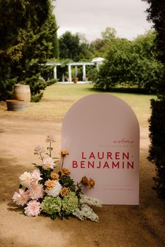 there is a sign that says lauren benjamini and flowers on the ground