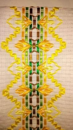 a close up view of an embroidered fabric with yellow, green and brown designs on it