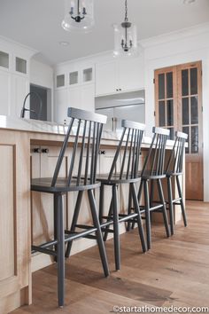 four chairs are sitting in front of the kitchen island