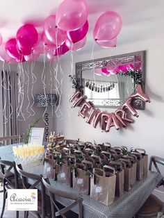 pink balloons are hanging from the ceiling above a dining room table with champagne and cake