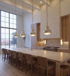 a large kitchen with an island and several lights hanging from it's ceiling over the counter