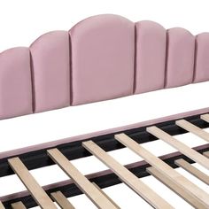 a pink bed frame with wooden slats on the top and bottom side, in front of a white background