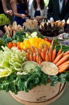 carrots, celery, and other vegetables are arranged in a wooden bowl