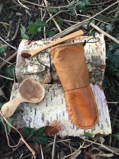 a pair of wooden spoons sitting on top of a piece of wood next to an oven mitt