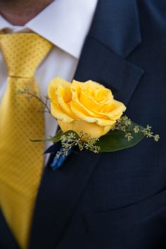 a man wearing a suit and tie with a yellow rose in his lapel flower