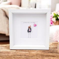 a white frame holding a pink balloon and a black bear with a heart on it