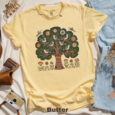 🌲✨ Embrace Scandinavian charm with this unique folk art T-shirt featuring birds and a floral tree design. Perfect for nature lovers and garden enthusiasts! 🌸🕊️  Comfort Colors 1717 is a fully customizable tee made 100% with ring-spun cotton. The soft-washed, garment-dyed fabric brings extra coziness to your wardrobe while the relaxed fit makes it an excellent daily choice. The double-needle stitching throughout the tee makes it highly durable while the lack of side-seams helps the shirt retai Nature-inspired Cotton Tops With Graphic Print, Nature-inspired Cotton T-shirt For Spring, Nature-inspired Cotton Tops With Screen Print, Nature-inspired Graphic Print T-shirt For Spring, Spring Nature-inspired Cotton T-shirt, Cottagecore Cotton Printed T-shirt, Spring Nature-inspired Short Sleeve T-shirt, Cottagecore Printed Cotton T-shirt, Nature-inspired Cotton T-shirt With Screen Print