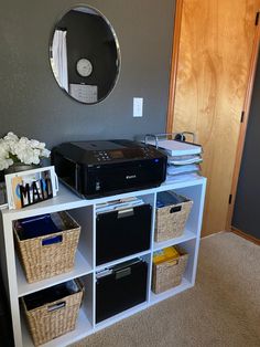 there is a printer on top of a shelf with bins and other items in front of it