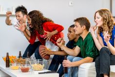 a group of young people sitting around a table with food and drinks on the table