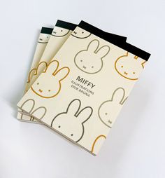 three notebooks on top of each other with bunny faces printed on the covers and black binding