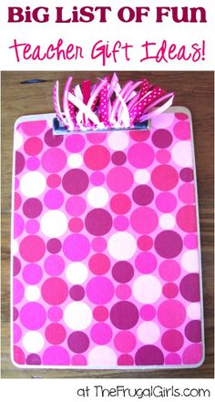 a pink and white polka dot clipboard on a wooden surface with ribbon attached to it