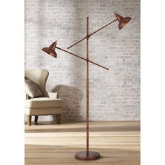 a floor lamp with three lights on it in front of a brick wall and chair