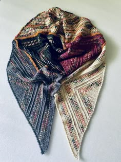 two knitted scarves sitting next to each other on top of a white surface