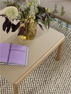 a vase with flowers and an open book on a coffee table