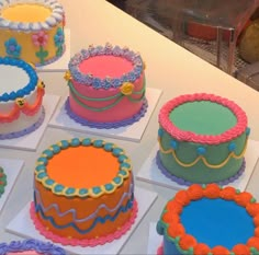 there are many cakes on the table with different colors and designs in them, including blue, orange, pink, yellow and green