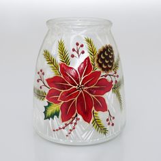 a glass vase decorated with holly, pine cones and poinsettis on a white background