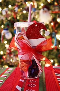 a cup filled with candy sitting on top of a table next to a christmas tree