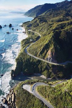 an aerial view of a winding road next to the ocean