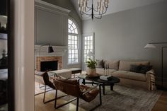 a living room filled with furniture and a fire place under a chandelier in front of a fireplace